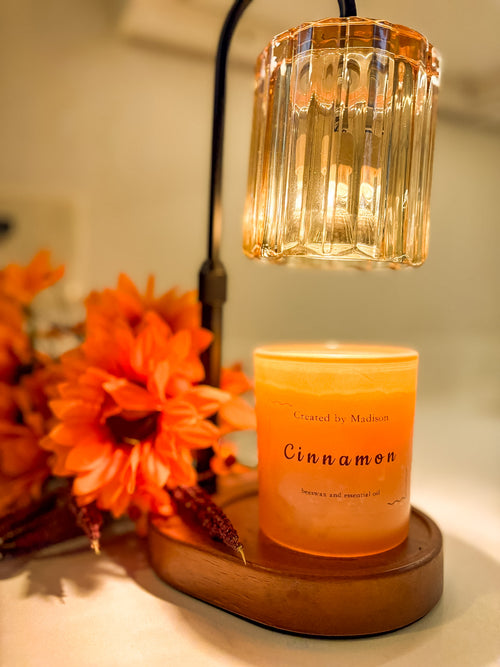 Cinnamon beeswax candle by Created by Madison glowing under a candle warmer with fall flowers