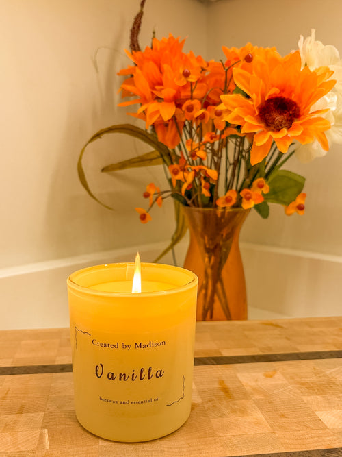 Vanilla beeswax candle by Created by Madison with orange flowers in background