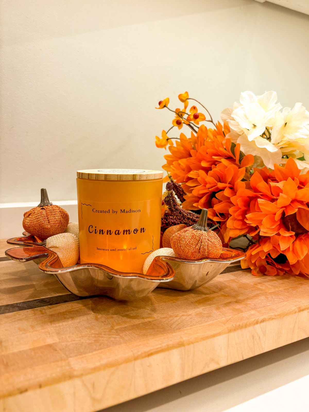 Cinnamon beeswax candle by Created by Madison in a decorative tray with pumpkins and fall flowers